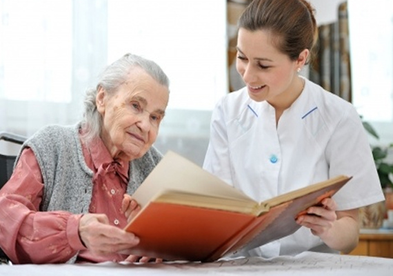 A caregiver looking through a photo album with an older adult