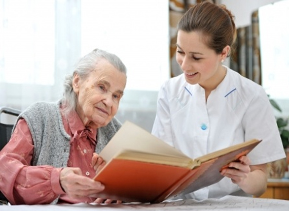 A companion sharing a photo album with an older adult