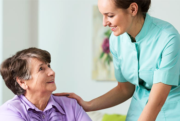 A caregiver sitting with an older adult at home